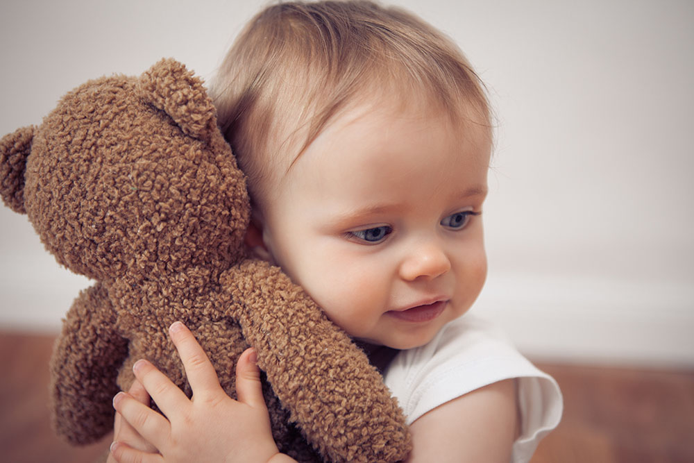 happy toddler cuddling stuffed animal at a Preschool & Daycare Serving New Braunfels, TX