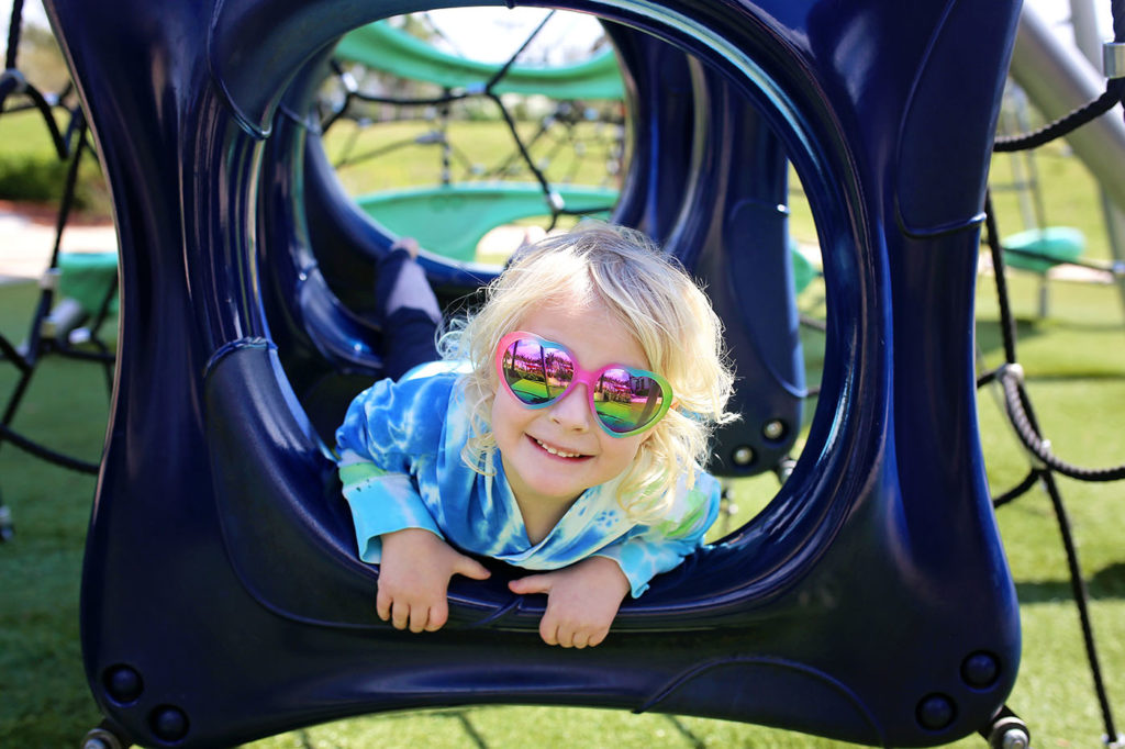 Girl With Sunglasses Smiling at the Playground at a Preschool & Daycare Serving New Braunfels, TX