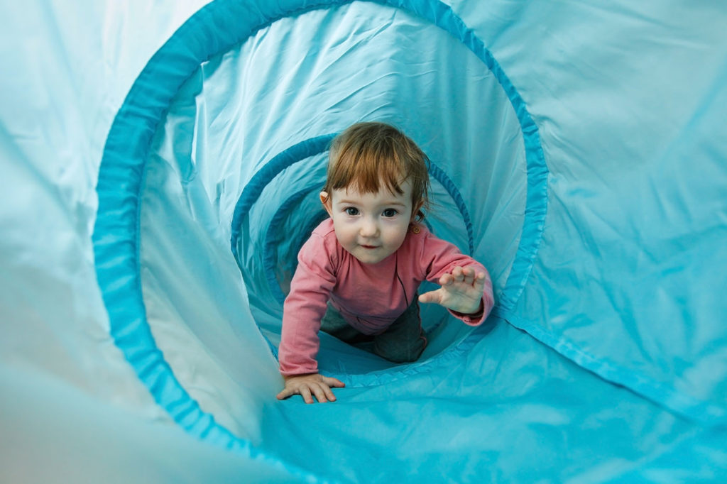 Small toddler playing in a tunnel tube at a Preschool & Daycare Serving New Braunfels, TX