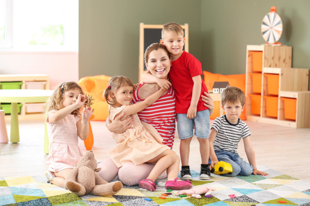 Nursery teacher with cute little children in kindergarten at a Preschool & Daycare Serving New Braunfels, TX